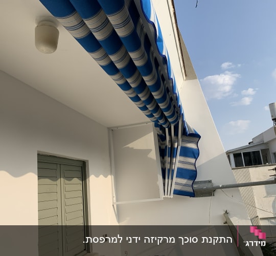 סוכך פסים כחול לבן מותקן על קיר חיצוני